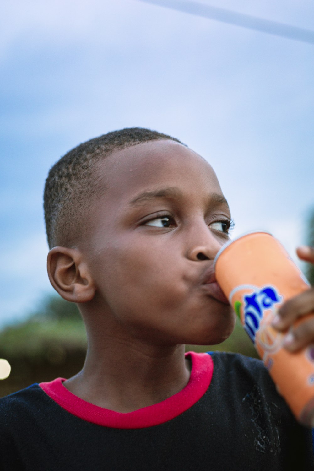 a young boy drinking a bottle of orange juice