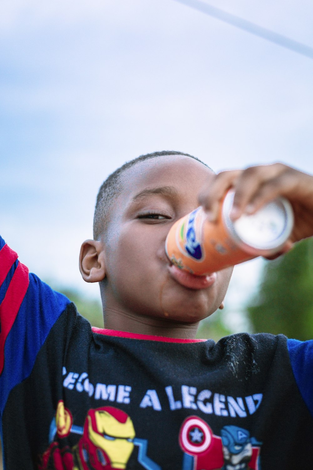 a young boy drinking a drink from a bottle