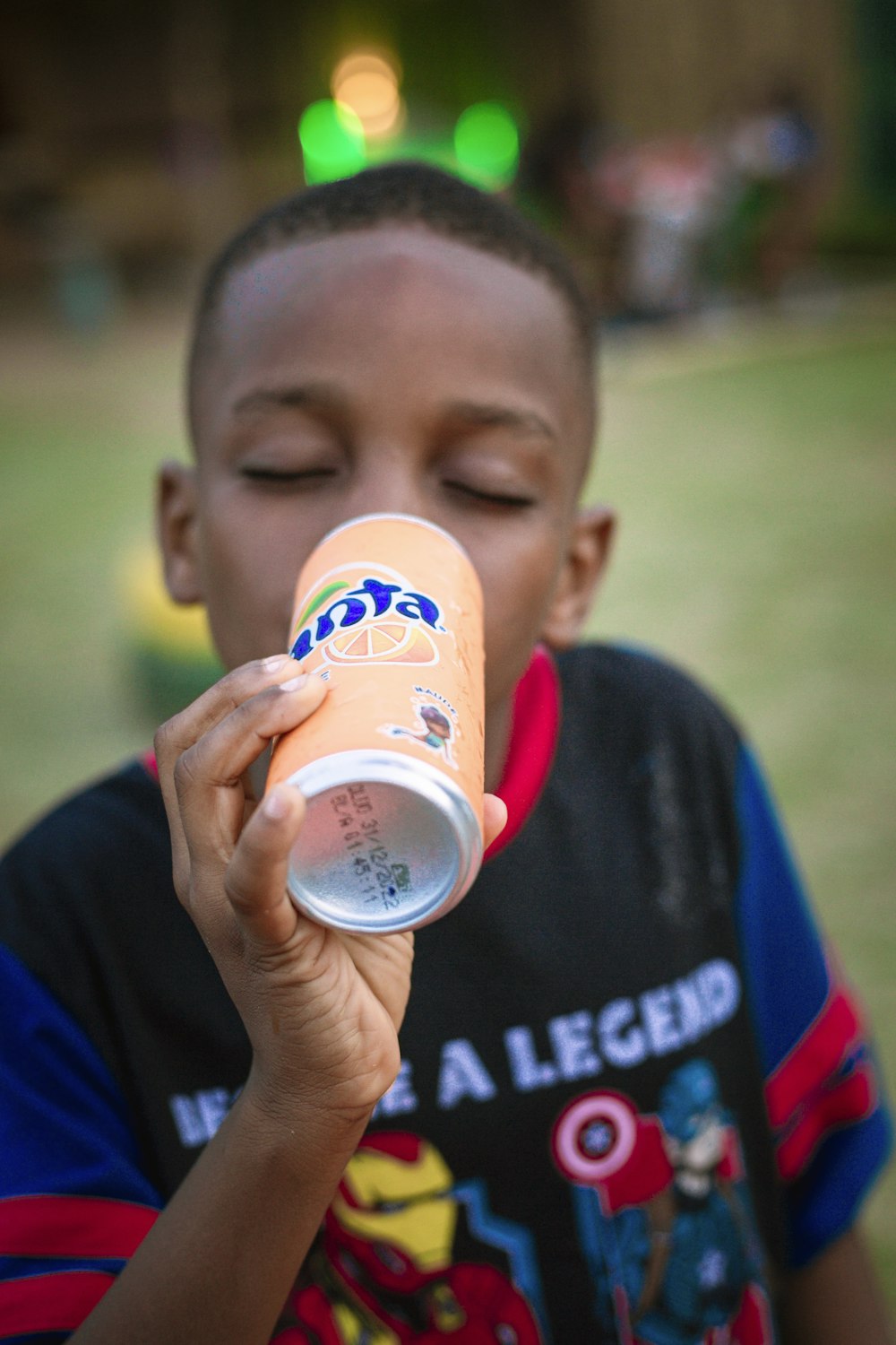 a young boy drinking a drink from a can