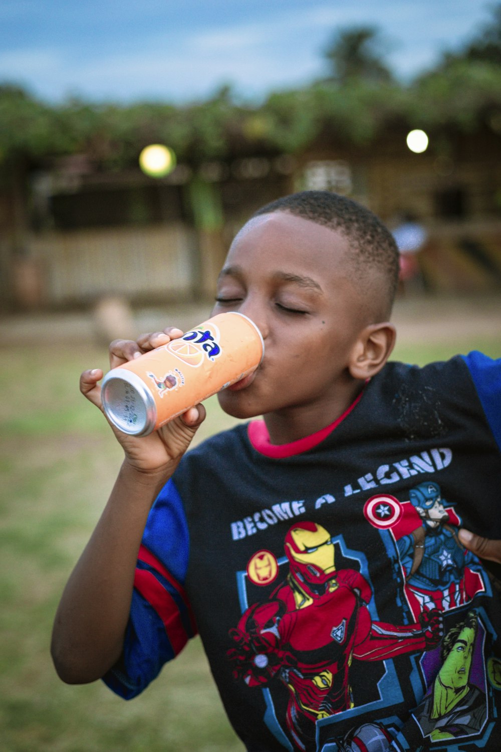 a young boy drinking a drink out of a can