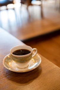 Elegant coffee cup on a dark petrol blue background with gold accents.