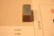 A rectangular stone stamp with an intricate red carving sits on a beige surface. To its side, there are two sheets of paper with text written in a script that appears to be East Asian characters.