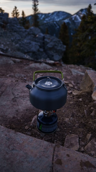 a kettle sitting on top of a rock covered ground