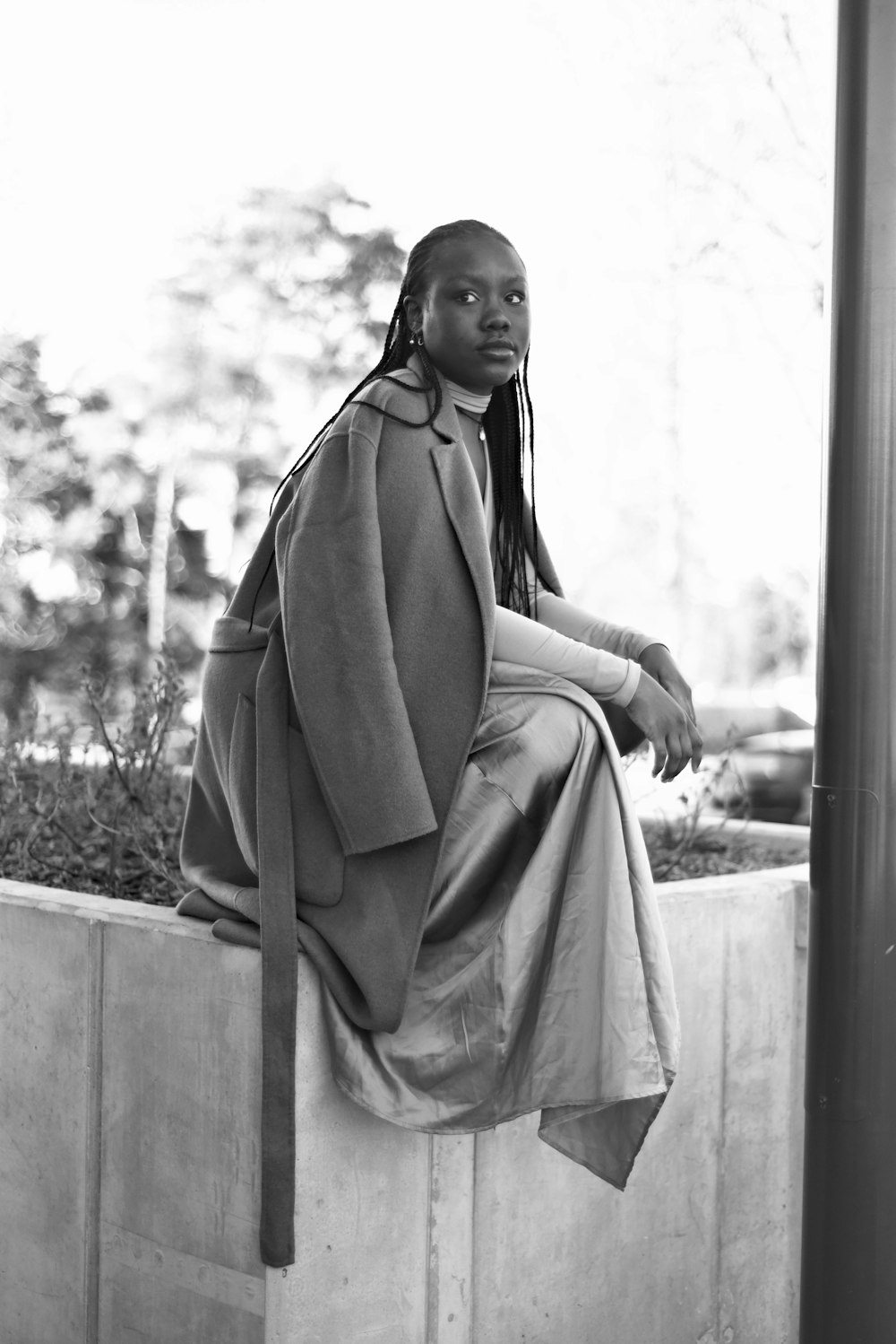 a black and white photo of a person sitting on a ledge