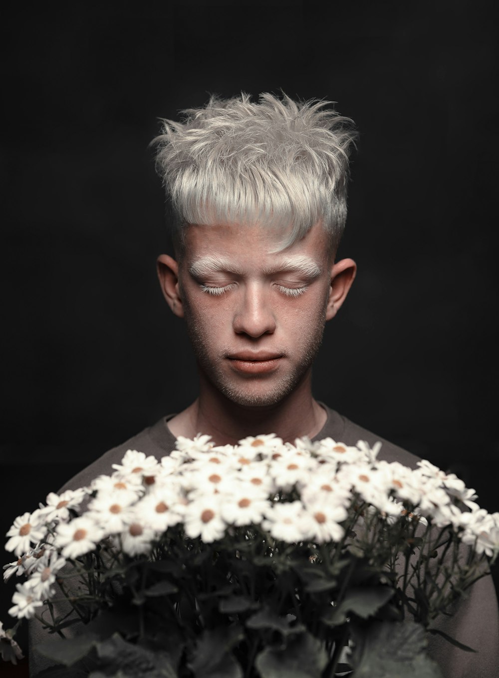 a man holding a bouquet of flowers in front of his face