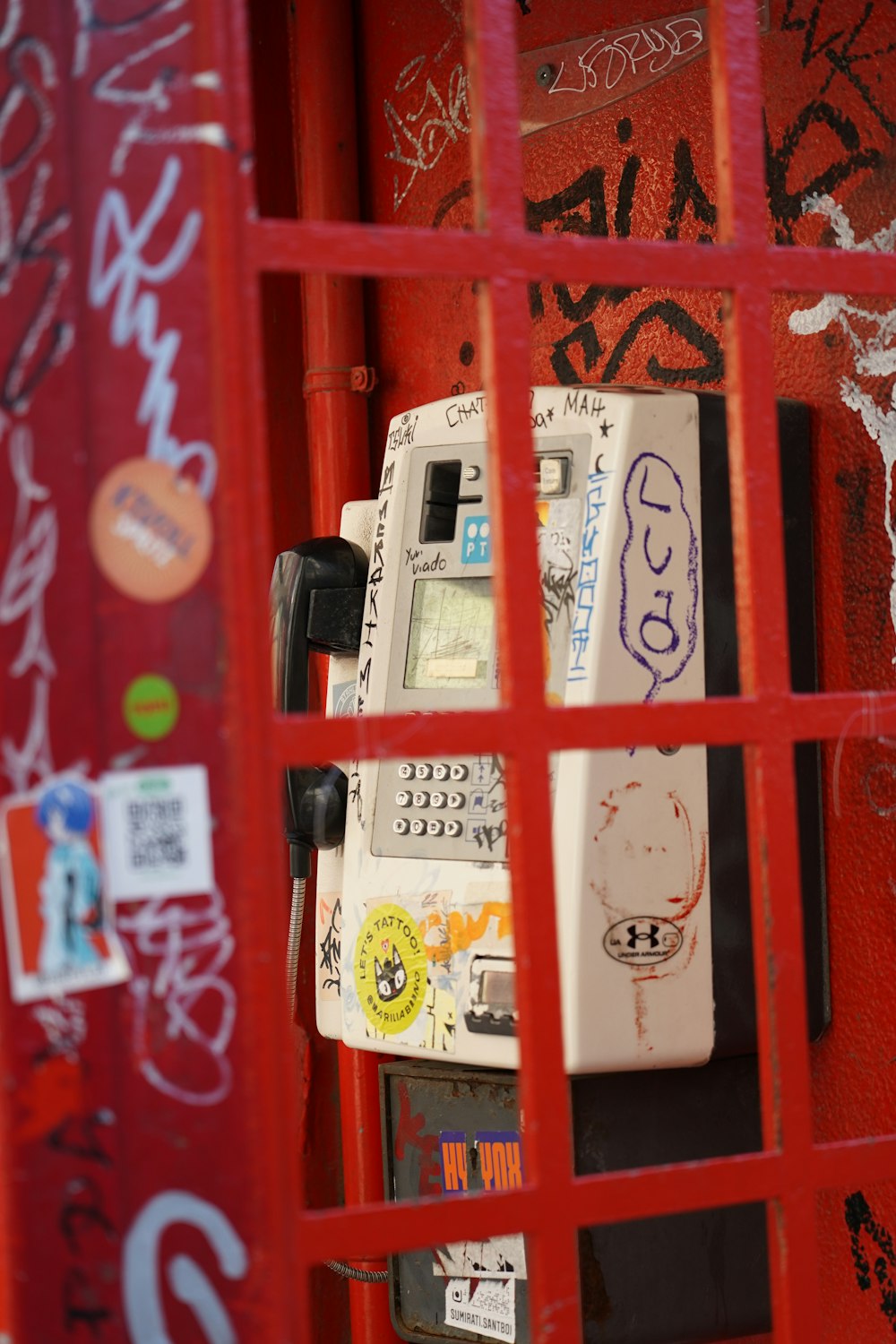 a red phone booth with graffiti on it