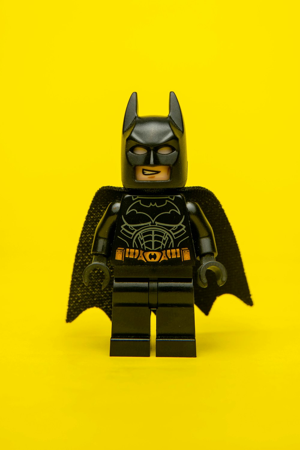 a lego batman standing on a yellow background