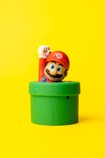 a toy mario in a green container on a yellow background