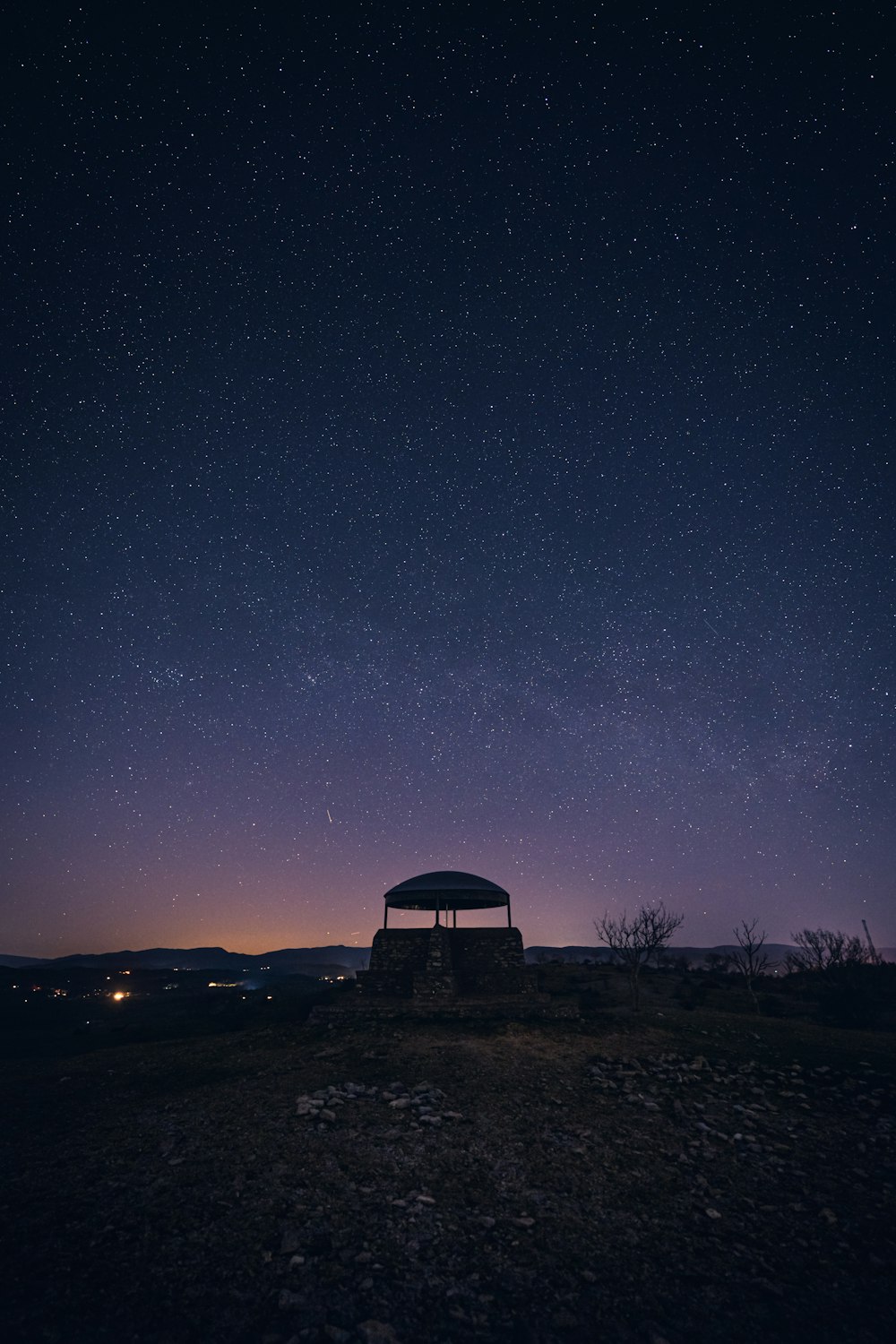 a gazebo sitting on top of a hill under a night sky