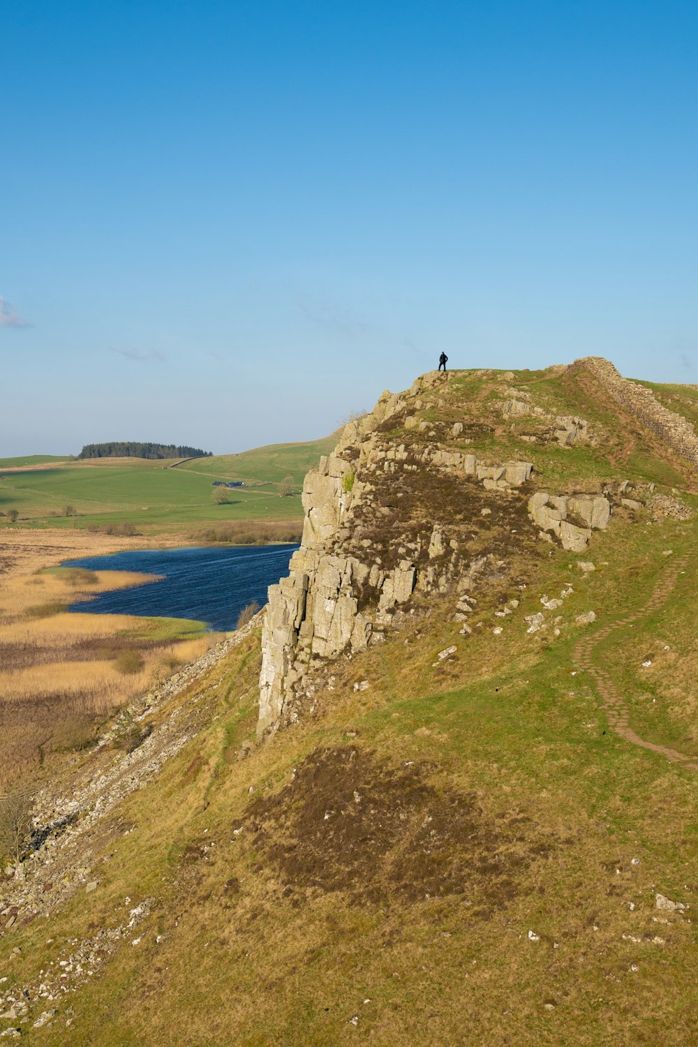 Una persona in piedi sulla cima di una collina vicino a un lago