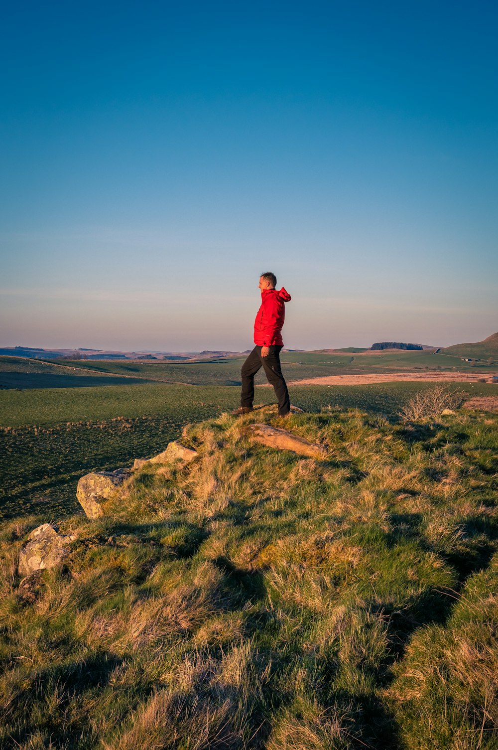 a man standing on top of a grass covered hill