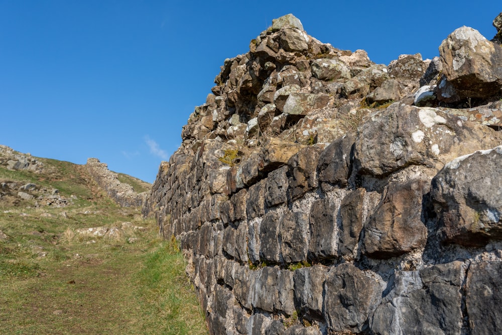 a stone wall with grass growing between it