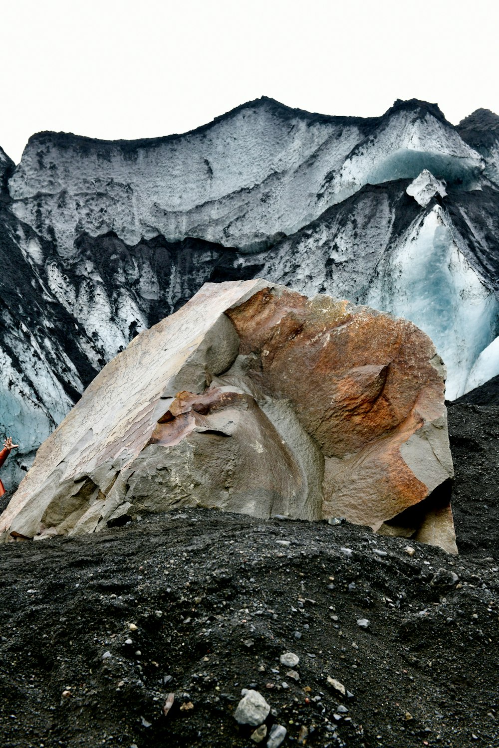 a man standing on top of a mountain next to a large rock