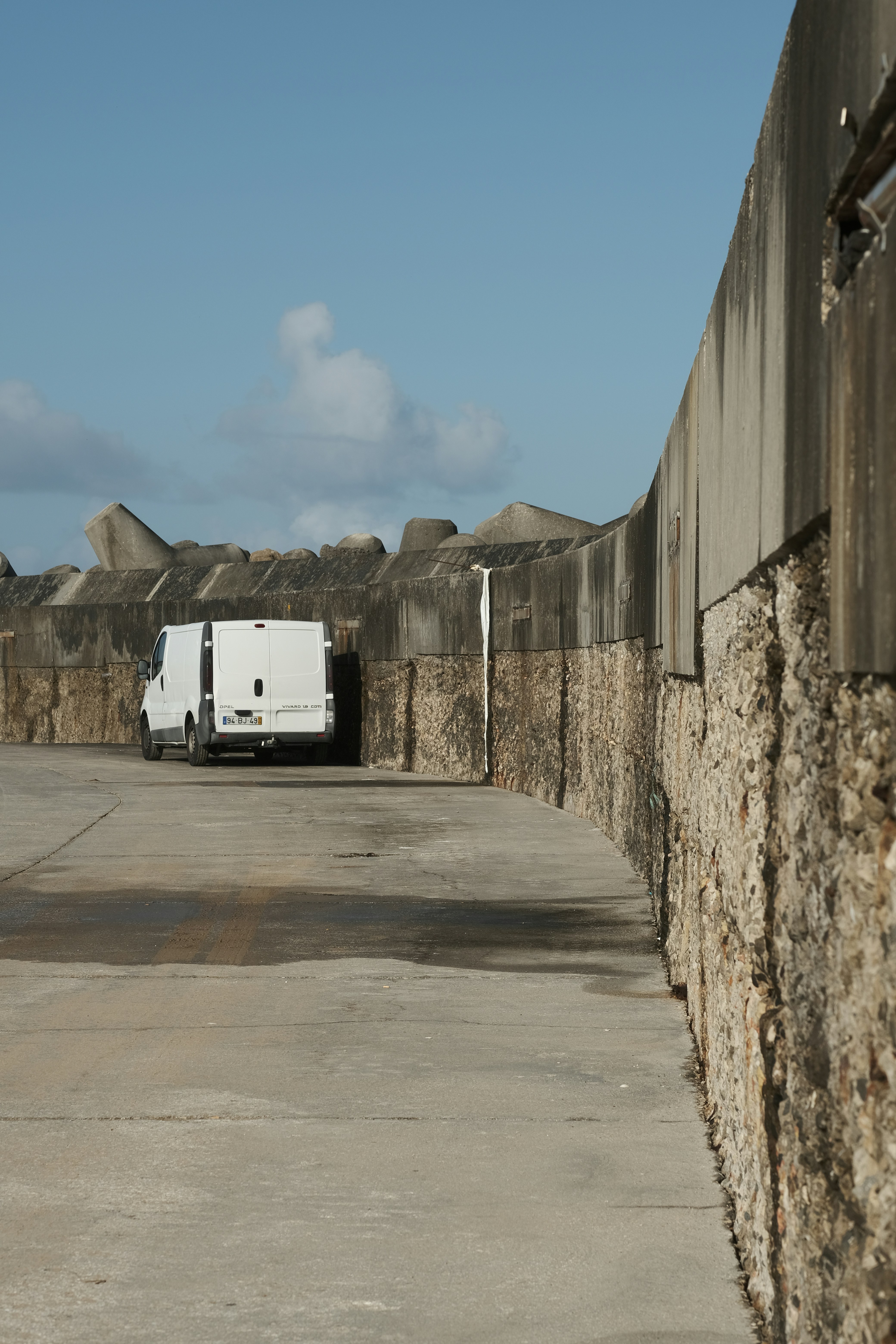 Un camion bianco parcheggiato in un parcheggio vicino a un muro di pietra
