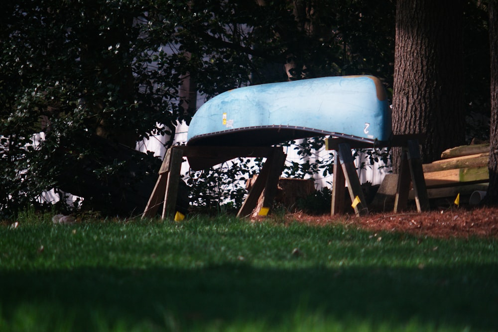 a blue boat sitting on top of a wooden bench
