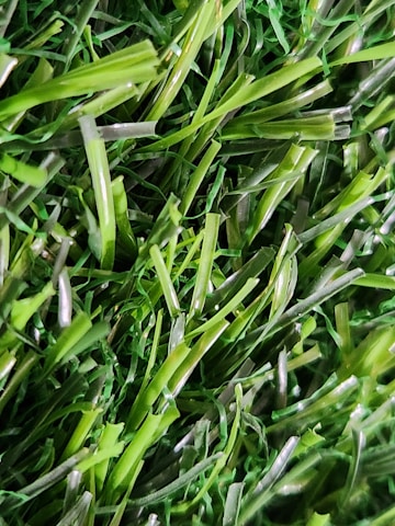 A close-up view of vibrant, green blades of synthetic grass with a realistic texture and sheen.