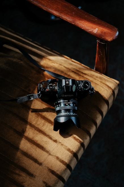 Close-up of a vintage film camera with black and yellow accents resting on a director’s chair
