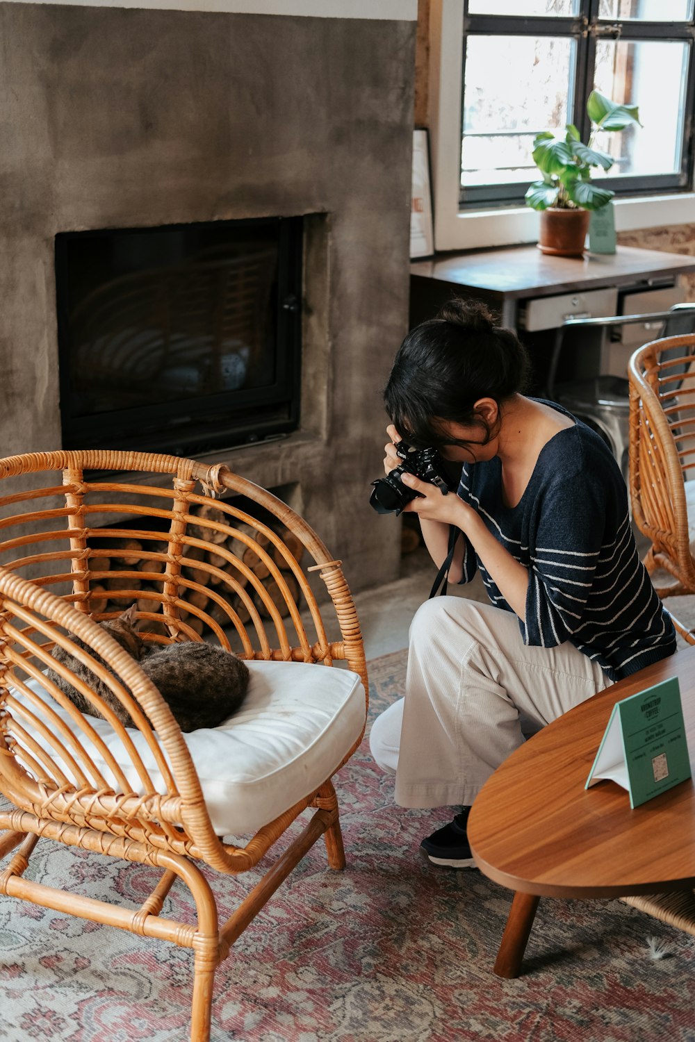 a woman taking a picture of a cat in a living room