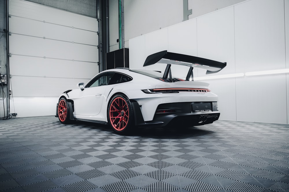 a white car with red rims parked in a garage