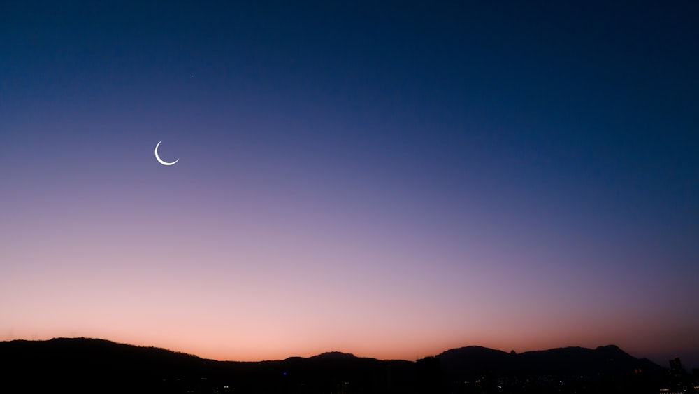 a crescent is seen in the night sky