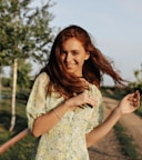 a woman standing on a dirt road holding a cell phone