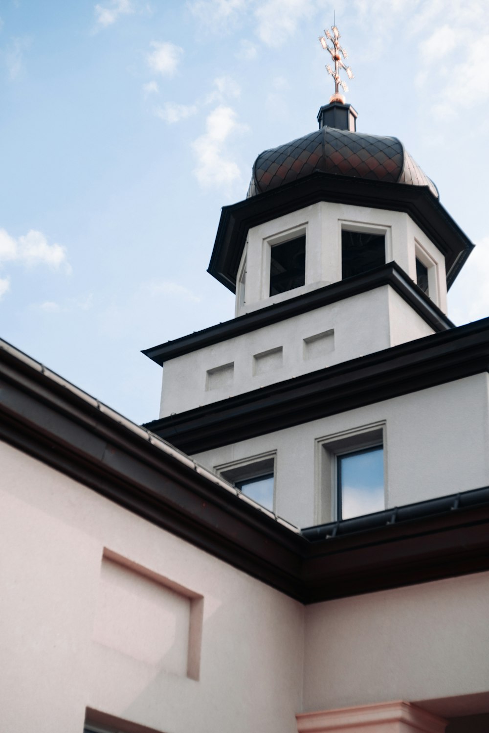 a white building with a black roof and a cross on top