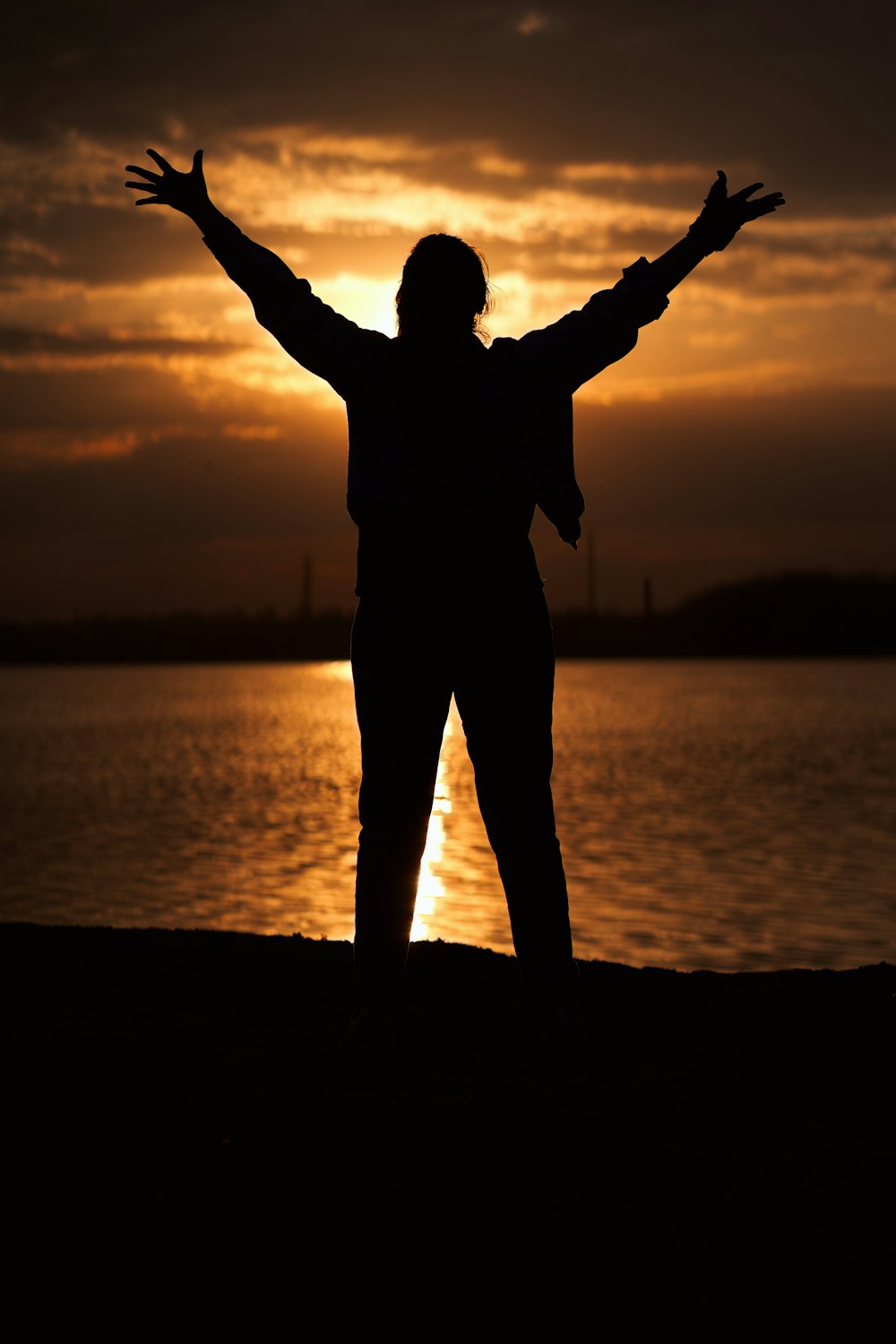 a person standing on a beach with their arms outstretched