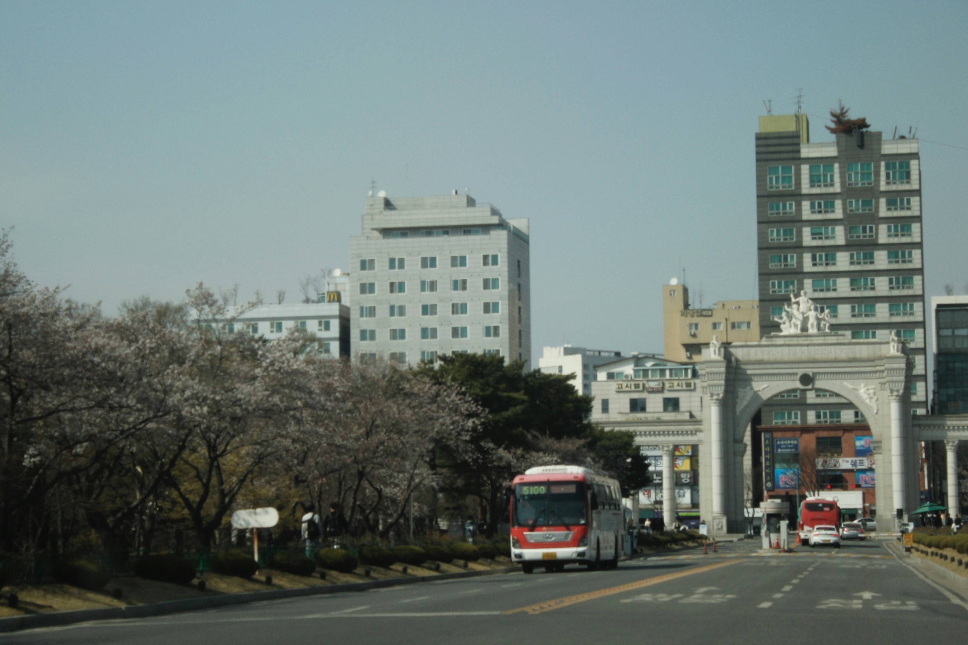 a red and white bus driving down a street next to tall buildings