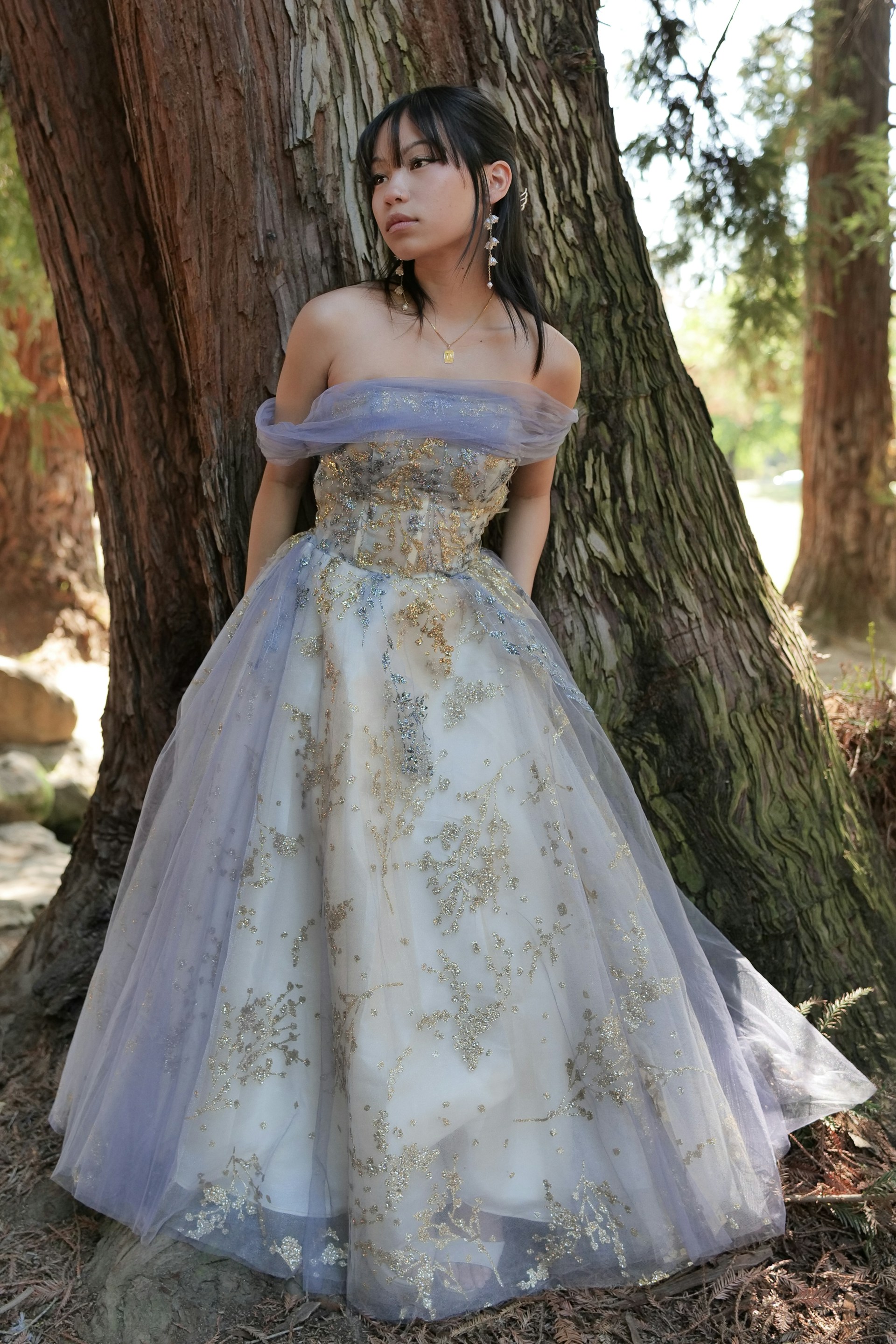 a woman in a dress standing next to a tree