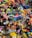 A colorful assortment of keychains and small plastic figurines featuring various cartoon characters and designs. The items are packed closely together, creating a vibrant and chaotic visual effect. Among the collection, there are wristbands, toys, and a variety of character-themed accessories.