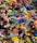 A colorful assortment of keychains and small plastic figurines featuring various cartoon characters and designs. The items are packed closely together, creating a vibrant and chaotic visual effect. Among the collection, there are wristbands, toys, and a variety of character-themed accessories.