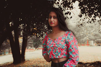 A vibrant photo of a woman wearing a flowing silk blouse in bright colors, standing in a sunlit urban park.