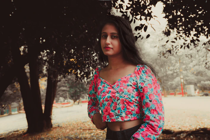 A vibrant photo of a woman wearing a flowing silk blouse in bright colors, standing in a sunlit urban park.