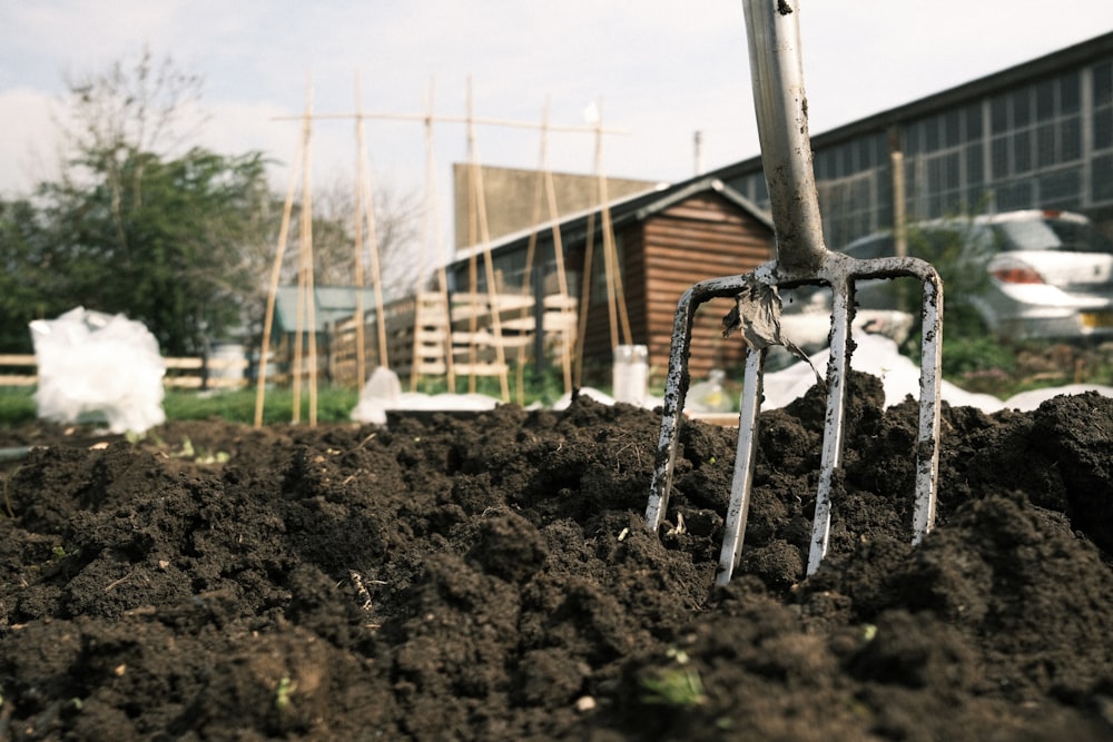 a garden fork stuck in a pile of dirt