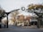 An archway on a street marks the entrance to Ottawa St., featuring a large clock at the center. The street is lined with small businesses and trees, with few people walking around. The area has an inviting and peaceful feel, typical of a small town or community street.