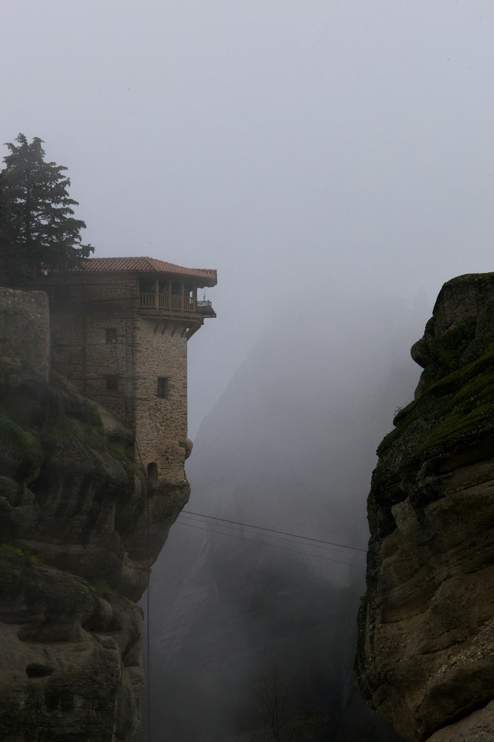 a foggy view of a building on a cliff