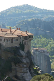 An ancient monastery nestled among green hills with colorful wildflowers in the foreground.
