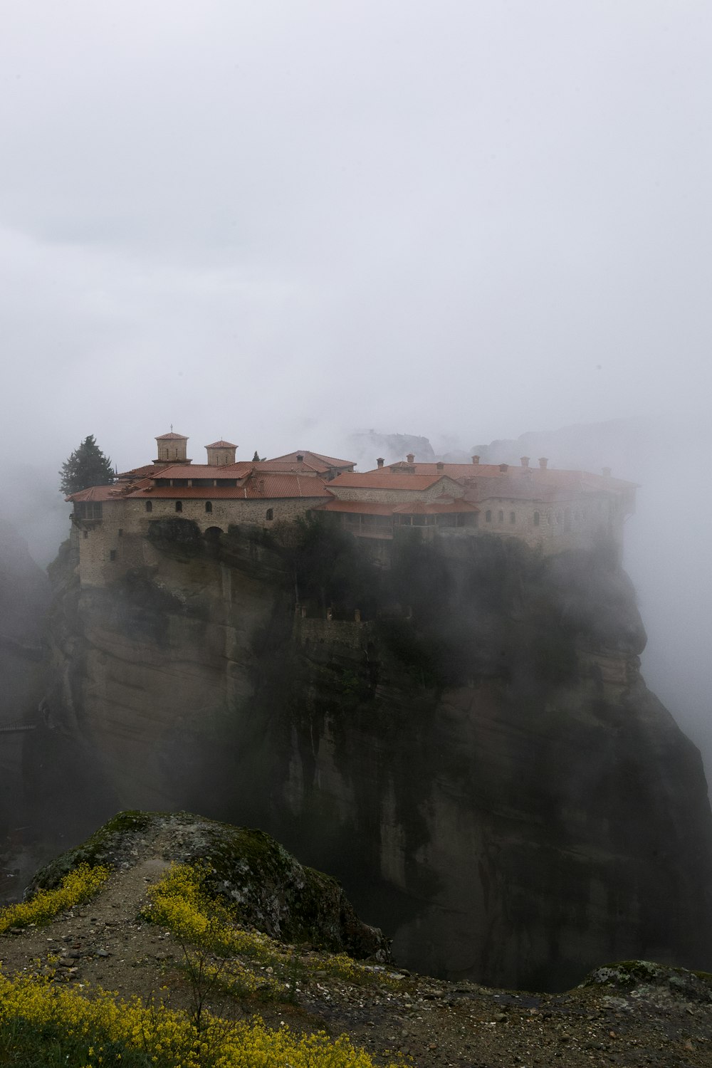 a castle perched on top of a cliff surrounded by fog