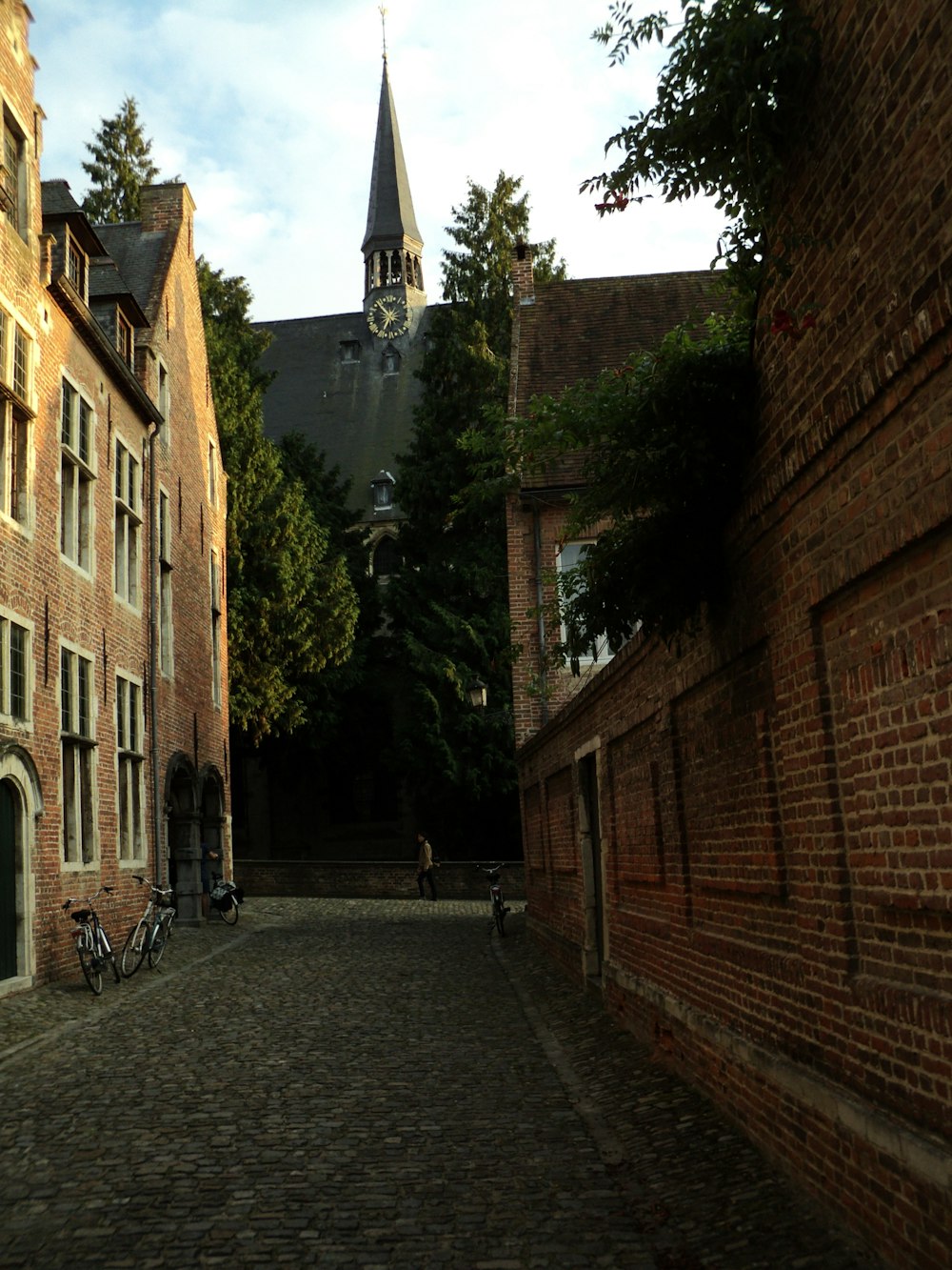 a cobblestone street with a church steeple in the background