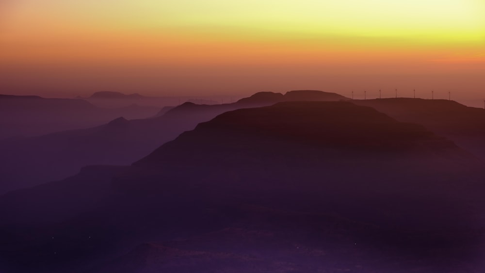 the sun is setting over a mountain range