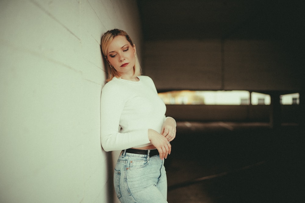 a woman leaning against a wall with her arms crossed