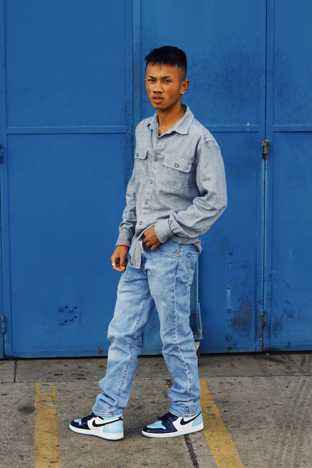 a young man standing in front of a blue wall