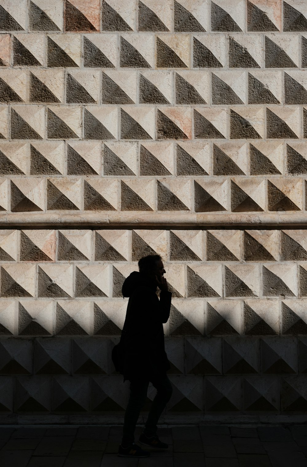 a person standing in front of a wall with a cell phone