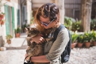 Volunteers warmly attending to a small cat during vaccination in an outdoor setting.