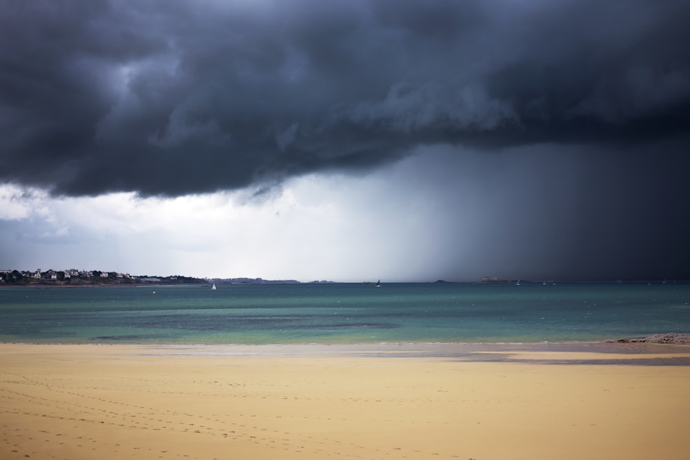 a storm is coming over the ocean on a beach