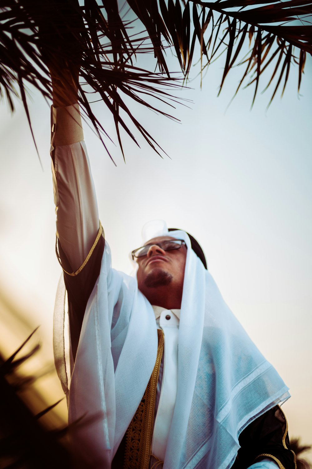a man in a white robe holding a palm tree