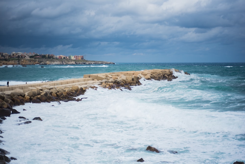 a person standing on a rock wall near the ocean