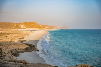 a sandy beach next to a body of water