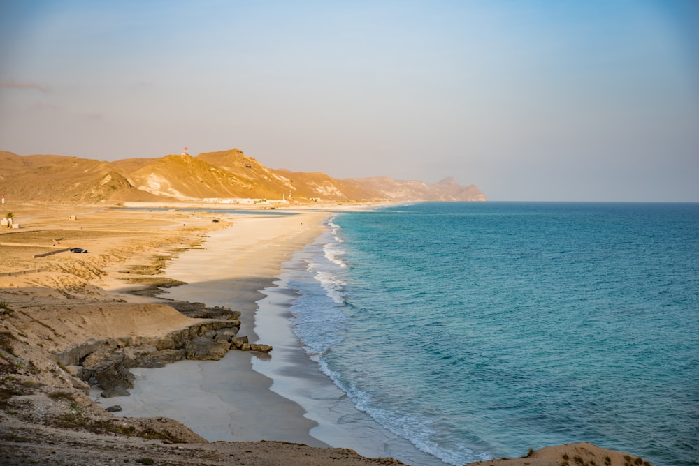 a sandy beach next to a body of water