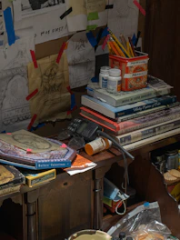 A colorful workspace with manga sketches and comic books spread out on a wooden desk.